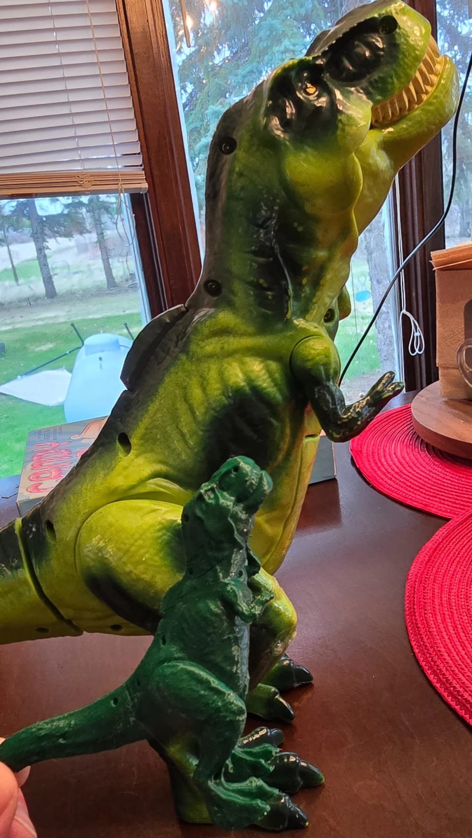 A green T-rex toy on a windowsill, scanned and reproduced